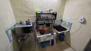 A compact kitchen with a tiled backsplash, a small countertop, and a sink. There are various kitchen items and containers on the counter and shelves. - Limestone House Apartment (Mérida)