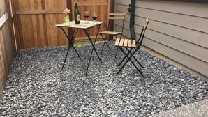 A patio area with a table and chairs, a bottle of wine, and a vase of flowers.