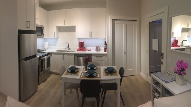 A compact kitchen with white cabinets, a refrigerator, a microwave, and a coffee maker.