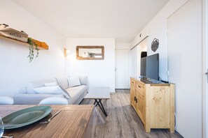 Ein modernes Wohnzimmer mit einem Holzesstisch, einer Couch und einem Fernseher auf einer Holzkommode.