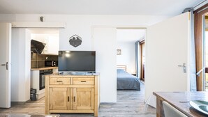 Een kleine keuken met houten kastjes, een inbouwoven en een flatscreen televisie.