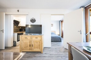 Eine kleine Küche mit Holzausstattung, einem eingebauten Backofen und einem Flachbildfernseher.