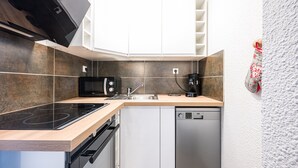 Een moderne keuken met een ingebouwde kookplaat, magnetron, spoelbak en vaatwasser.