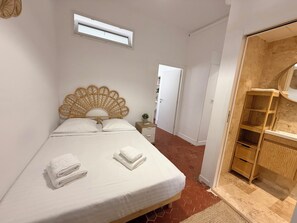 Een slaapkamer met een bed, een houten hoofdbord, een nachtkastje, een kledingkast en een airconditioning.
