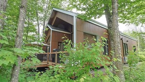 Eine moderne Holzhütte mit Terrasse und großem Fenster.