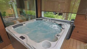 Ein Whirlpool mit Bedienfeld, ein Fenster mit Blick auf Grünflächen und Holzboden.