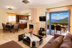 A modern living room with a fireplace, dining area, and a balcony with a scenic view.