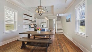 A spacious kitchen with a central island, wooden flooring, and a staircase leading to an upper level. - Huge New Home w/ Outdoor Space, Walk to Streetcar! (New Orleans)