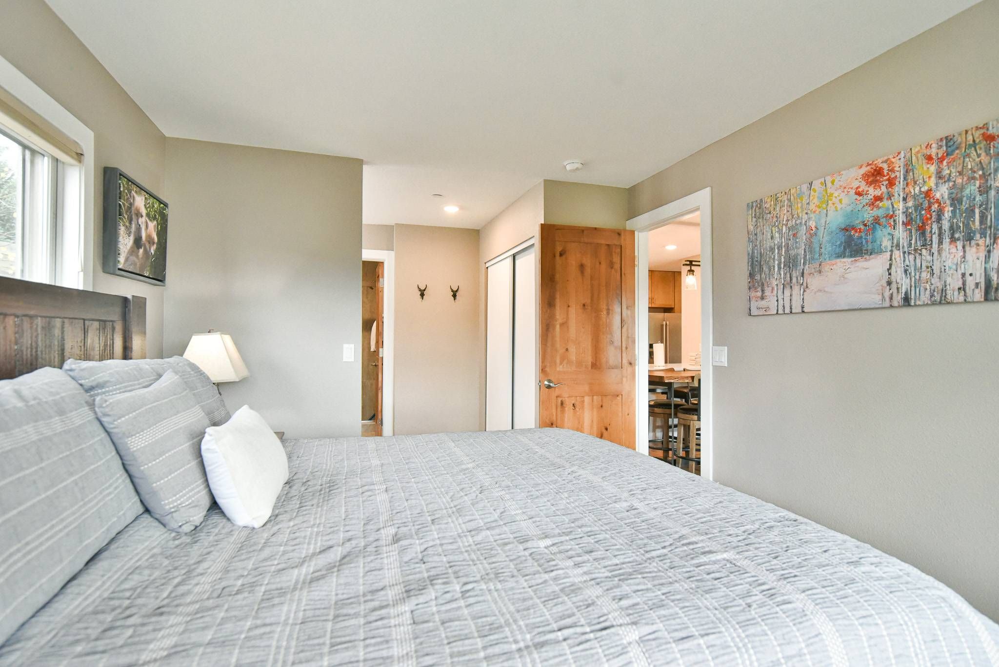 A bedroom with a bed, a nightstand, a lamp, and a painting on the wall.