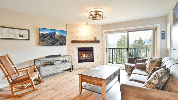 A living room with a fireplace, a sofa, a rocking chair, and a television. - Ski • Paddle • Hike | Lake Dillon | Hot Tub (Frisco)