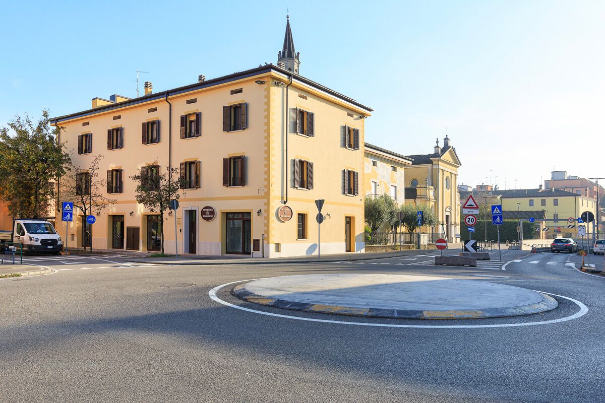 Una glorieta con un edificio amarillo que tiene múltiples ventanas y una pequeña torre.