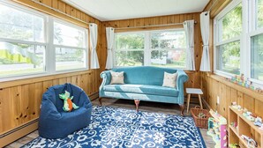 Una habitación acogedora con un sofá color turquesa, un sillón de peluche azul y una alfombra estampada.