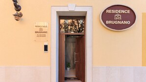 Hotellin sisäänkäynti, jossa on puuovi, vastaanottotiski ja kyltti, jossa lukee: ”RESIDENCE BRUGNANO”.