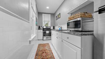 A modern kitchen with white cabinetry, stainless steel appliances, and a decorative rug.