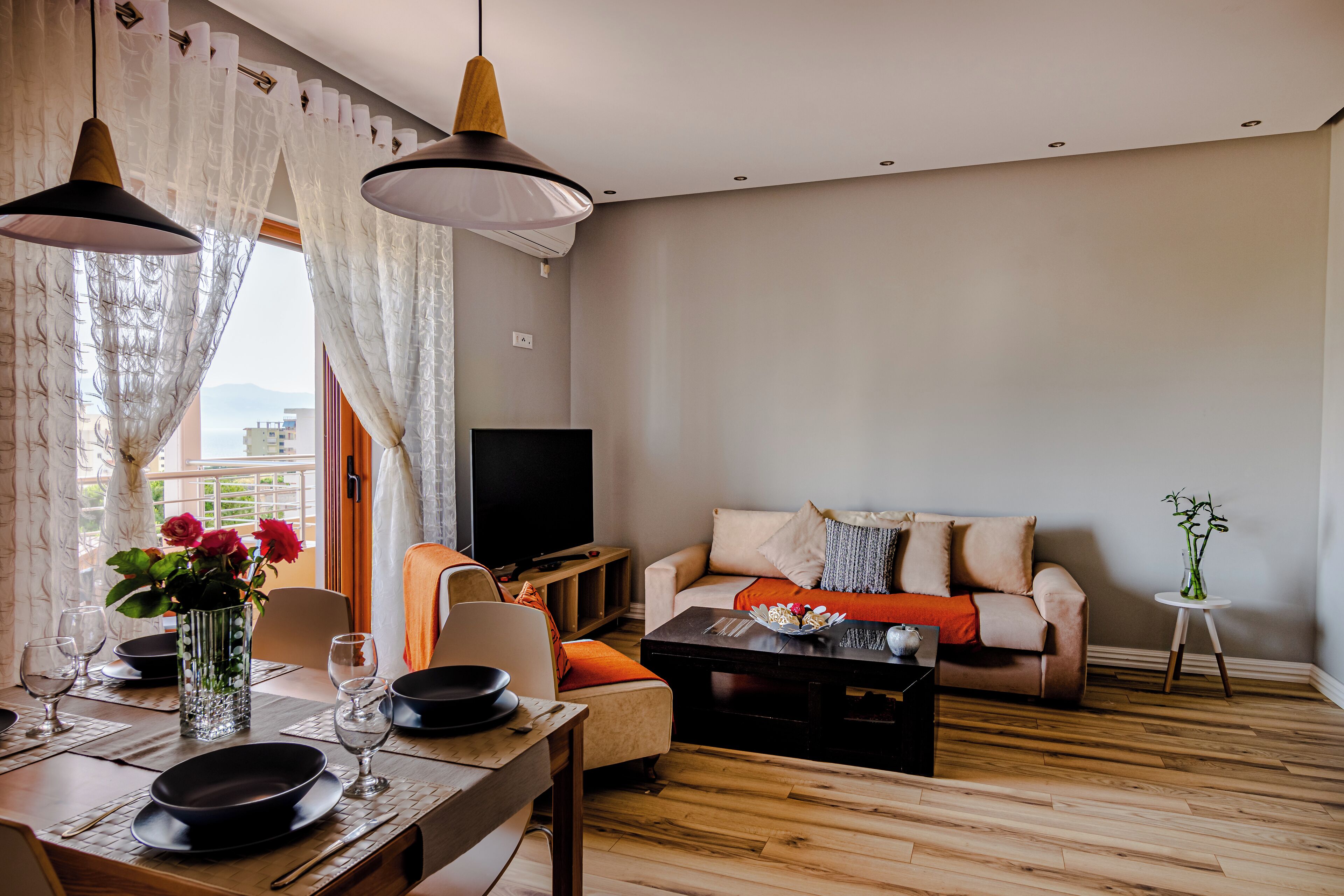 A living room with a sofa, coffee table, and dining table set for a meal.