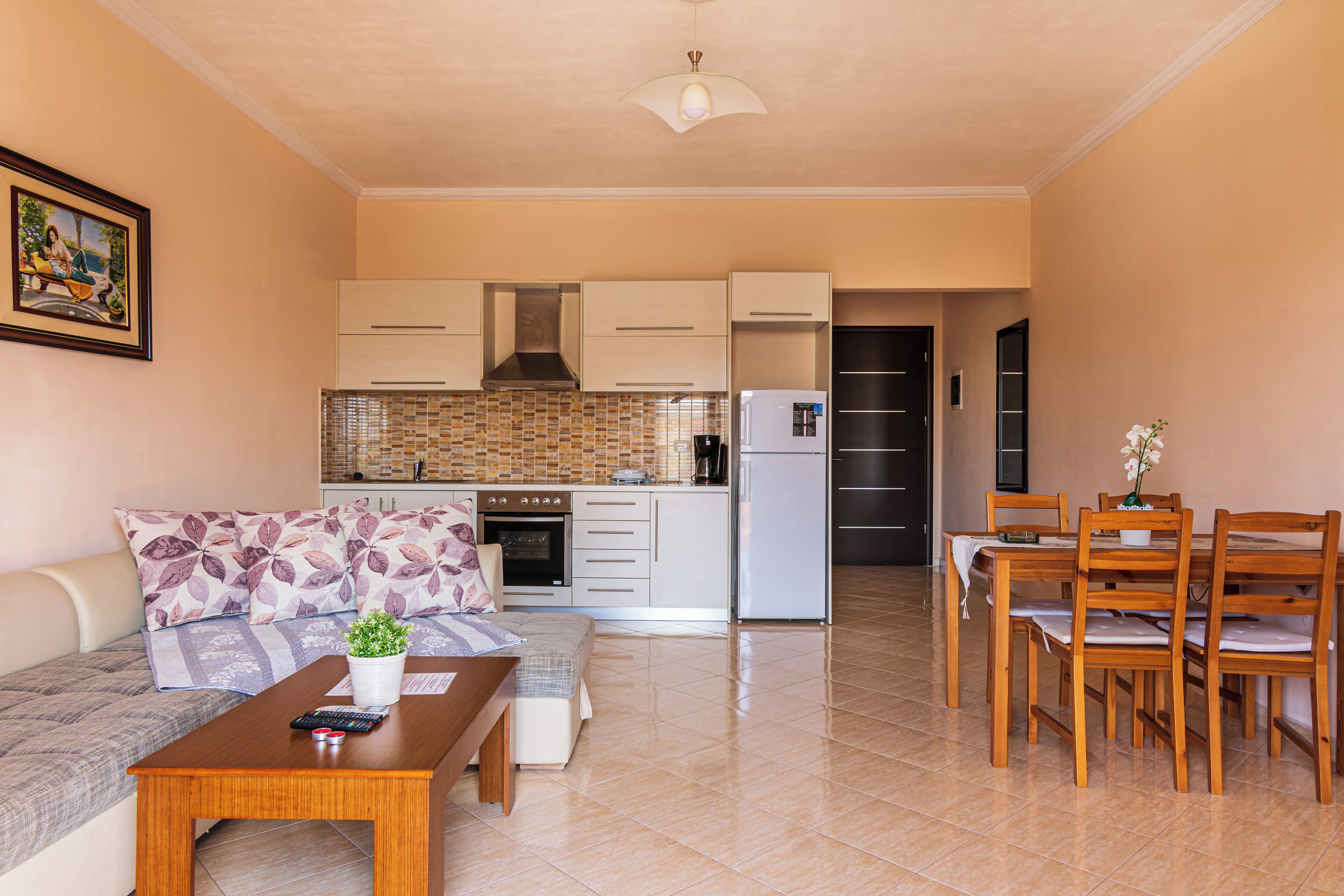 A compact living space with a kitchenette, a dining area, and a seating area with a sofa and coffee table.