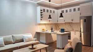 A modern kitchen with white cabinets, a central island, and a built-in refrigerator. - Great Alexander Suites (Sarande)