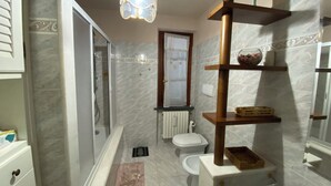 A bathroom with a shower, toilet, and a vanity with shelves.