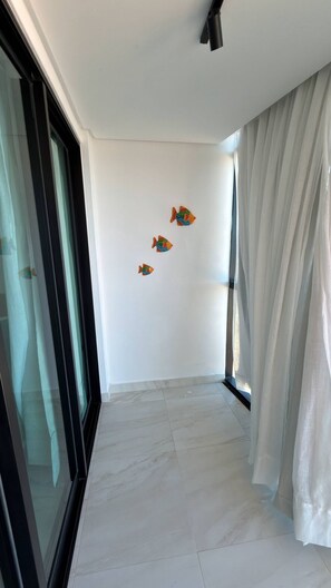 Ein Flur mit Glastür, weißen Wänden und einem Fenster mit weißen Vorhängen.