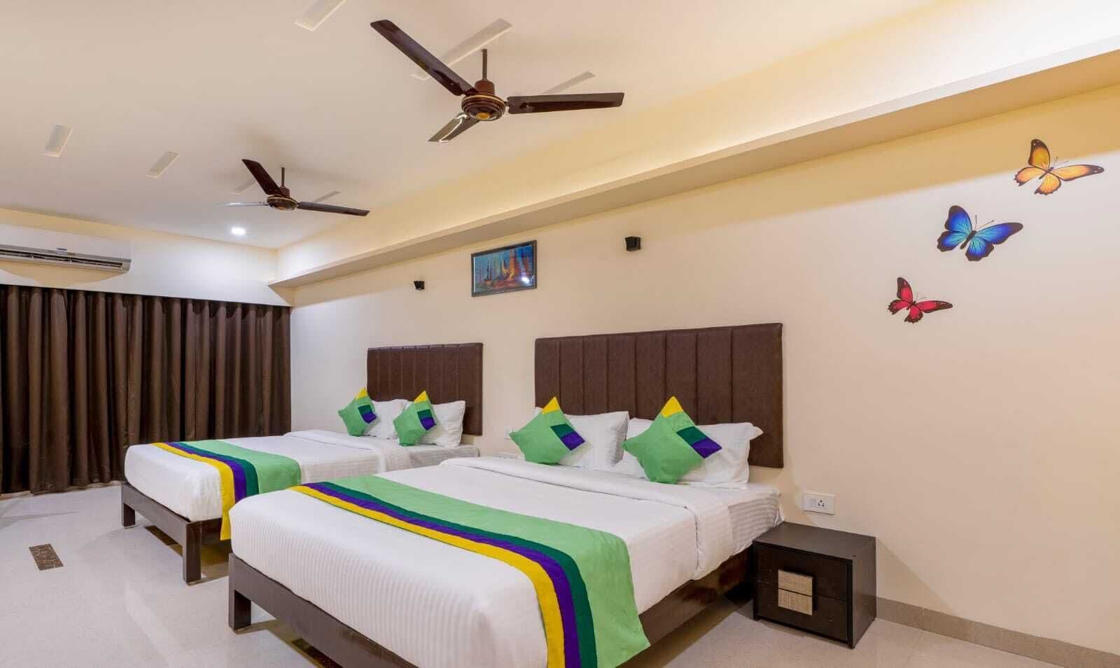 Une chambre d’hôtel avec deux lits, un ventilateur de plafond, un appareil de climatisation et des autocollants décoratifs représentant des papillons.