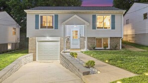 A two-story residential house with a garage, a front door, and a small front yard with a pathway. - Family Retreat w/ Hot Tub near Zoo & Forest Park (St. Louis)