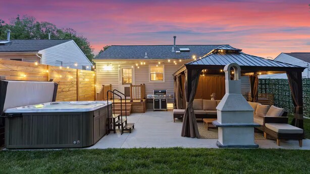 A backyard with a hot tub, outdoor seating, a pergola, and string lights. - Family Retreat w/ Hot Tub near Zoo & Forest Park (St. Louis)