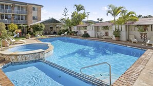 Una piscina rettangolare con bordo piastrellato e una piccola area idromassaggio.