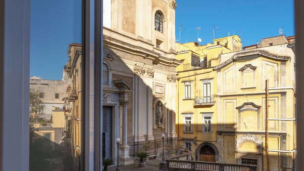 Un patio con una escalera que lleva a un edificio de arquitectura clásica, que incluye columnas y estatuas.