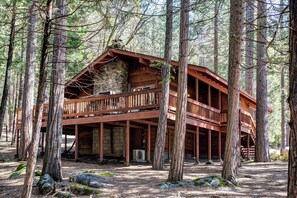 A cabin with a wooden exterior, a stone foundation, and a balcony. - Robin's Nest (Yosemite National Park)