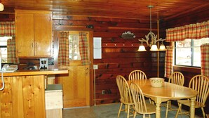 Ein Holzblockhaus-Interieur mit Küchenzeile, Esstisch und Stühlen.