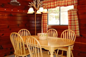A wooden dining table with four chairs, a bowl, and a wall-mounted light fixture. - Cubby's Den (Yosemite National Park)