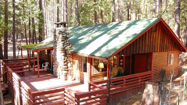 Eine rustikale Holzhütte mit Steinofen, Holzbalkon und überdachter Veranda.