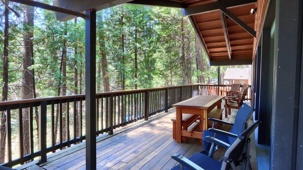 Eine Holzterrasse mit Tisch und Stühlen mit Blick auf einen Wald.