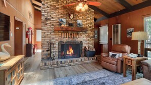 Ein gemütliches Wohnzimmer mit Kamin aus Backsteinen, Ledersessel und Deckenventilator.