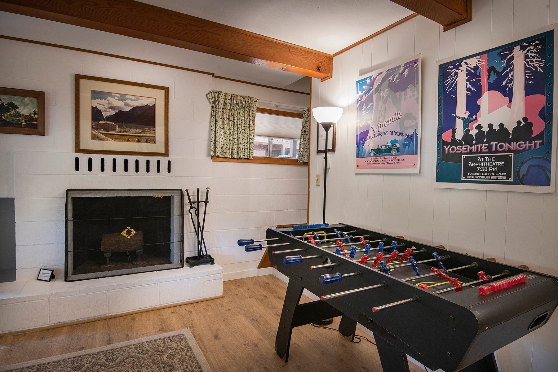A cozy room with a fireplace, a foosball table, and framed pictures on the wall.