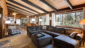 A cozy living room with a sectional sofa, a dining area, and large windows offering a view of the outdoors. - Bird's Eye View (Yosemite National Park)