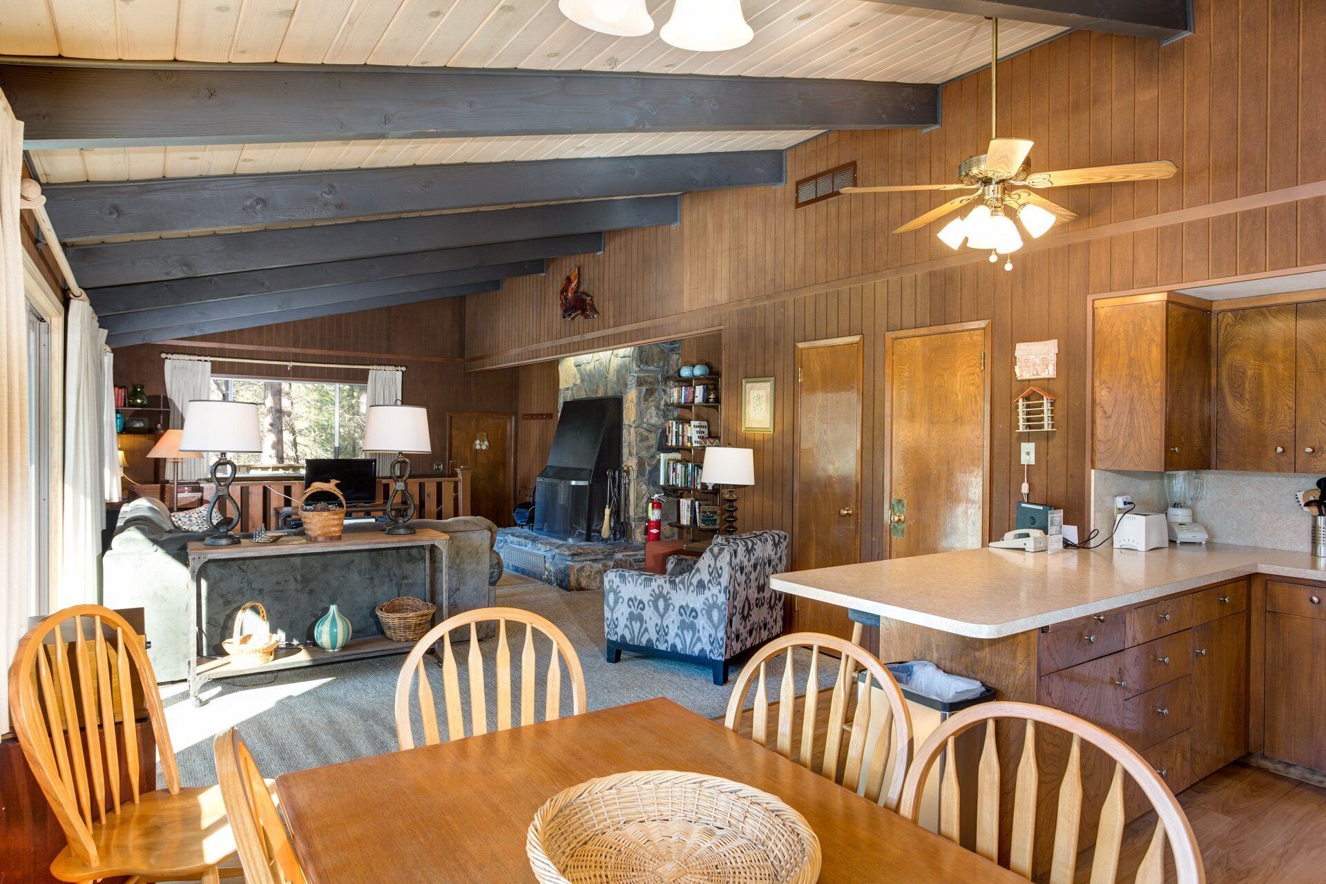 A cozy cabin interior with a dining area, kitchen, and fireplace.