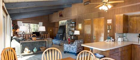 A cozy cabin interior with a dining area, kitchen, and fireplace.