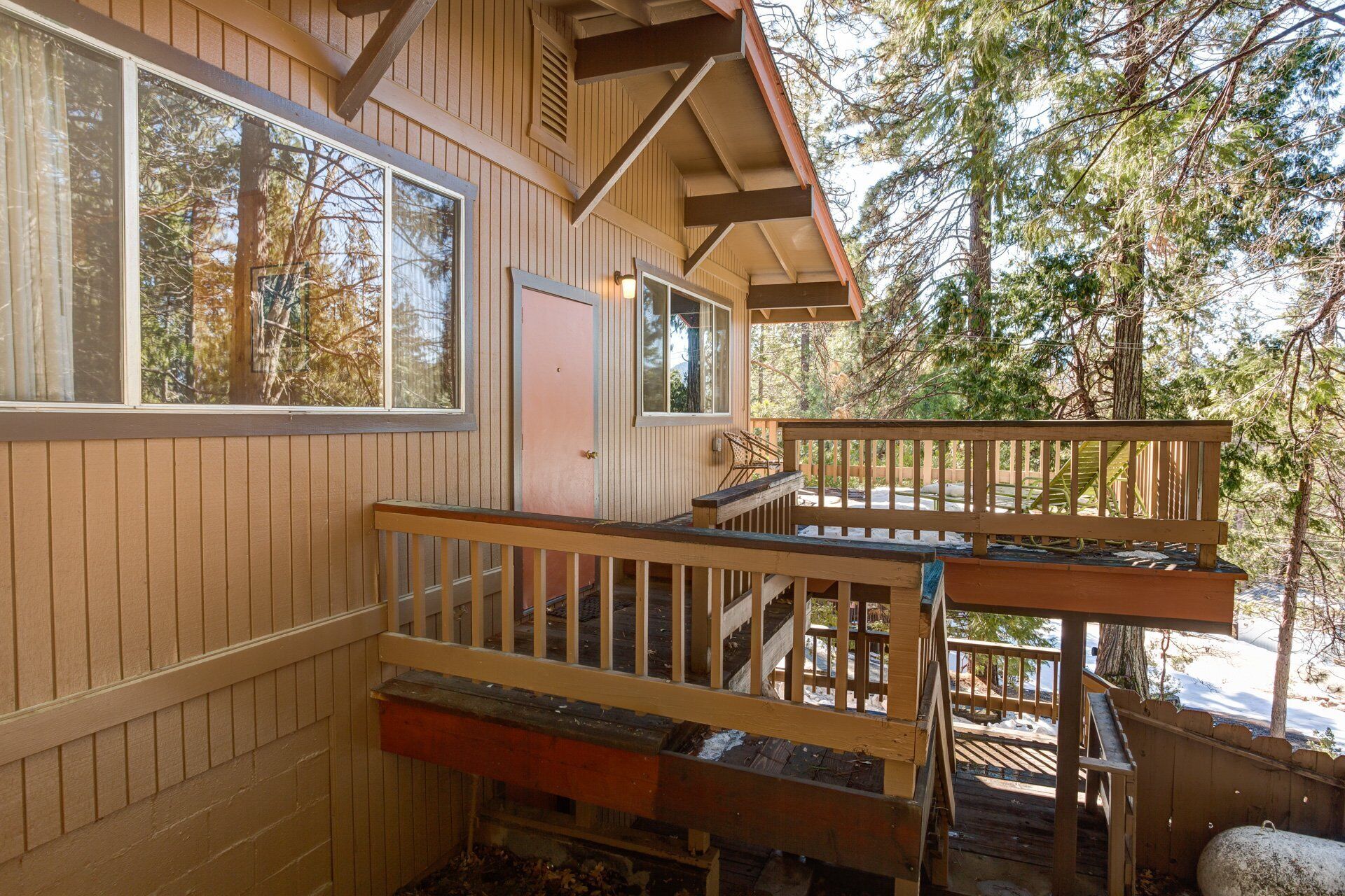 A cabin with a wooden exterior, a deck, and a staircase leading to a second level.