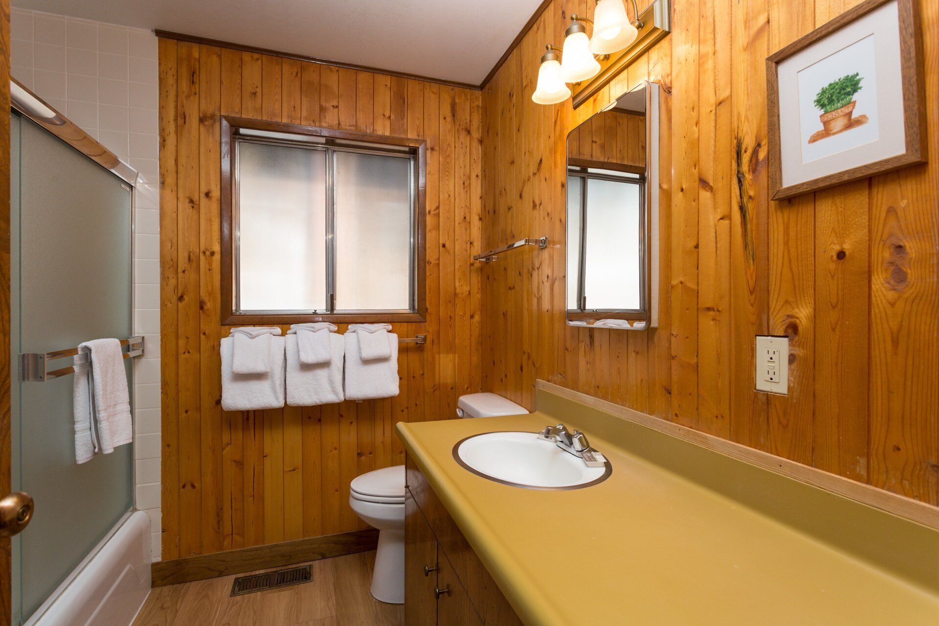 Ein Badezimmer mit Holzvertäfelung, Toilette, Waschbecken und Dusche.