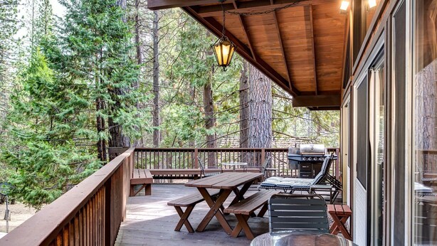 A wooden deck with picnic tables and a grill, surrounded by trees. - Star Gazers (Yosemite National Park)