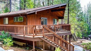 A wooden cabin with a balcony and a staircase leading to a second level. - Star Gazers (Yosemite National Park)