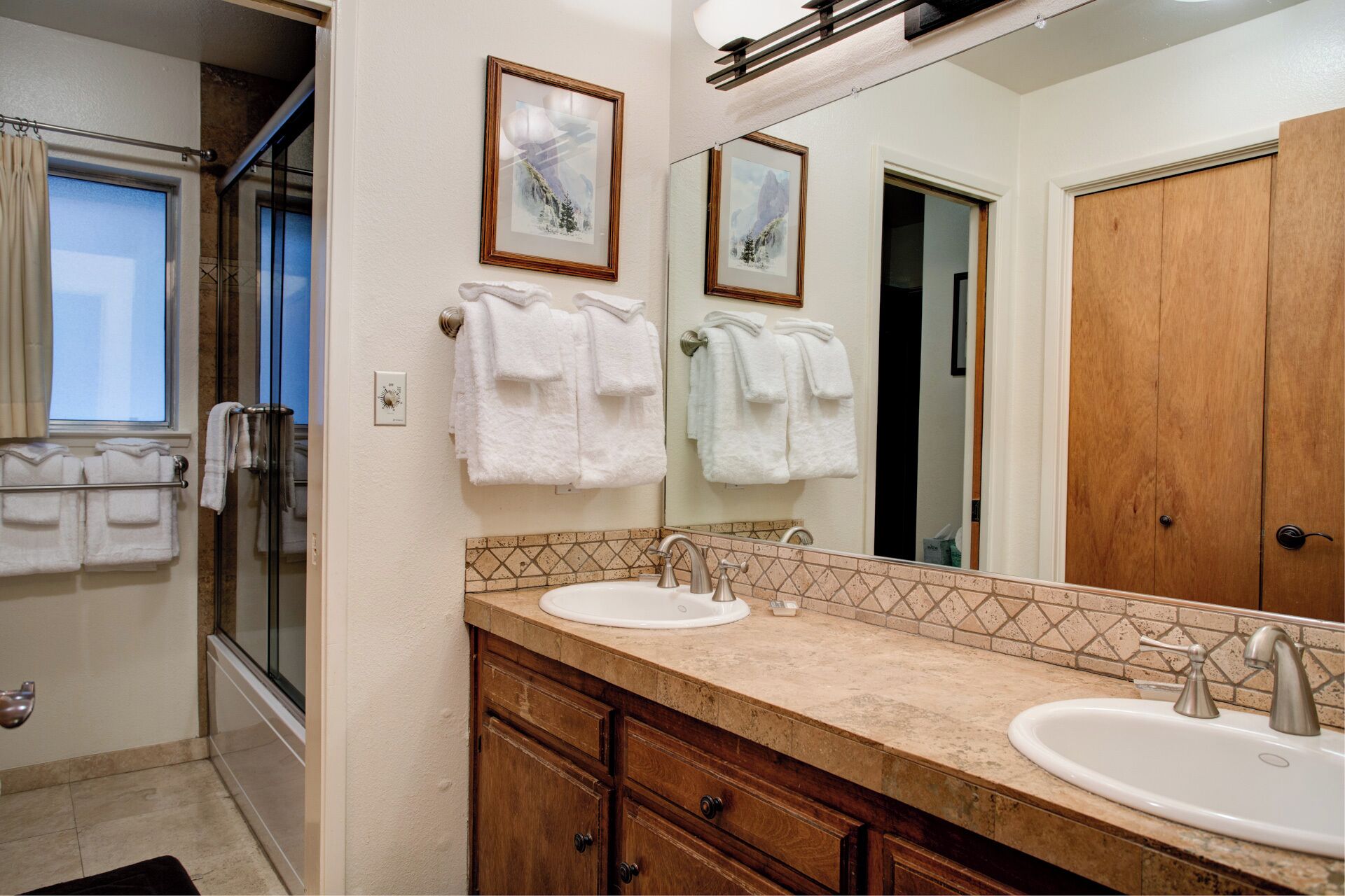 Un baño con dos lavamanos, un espejo grande y una ducha.