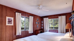 A bedroom with two beds, wooden walls, a ceiling fan, and large windows with curtains. - Star Gazers (Yosemite National Park)
