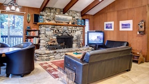 A cozy living room with a stone fireplace, leather furniture, and a television. - Star Gazers (Yosemite National Park)
