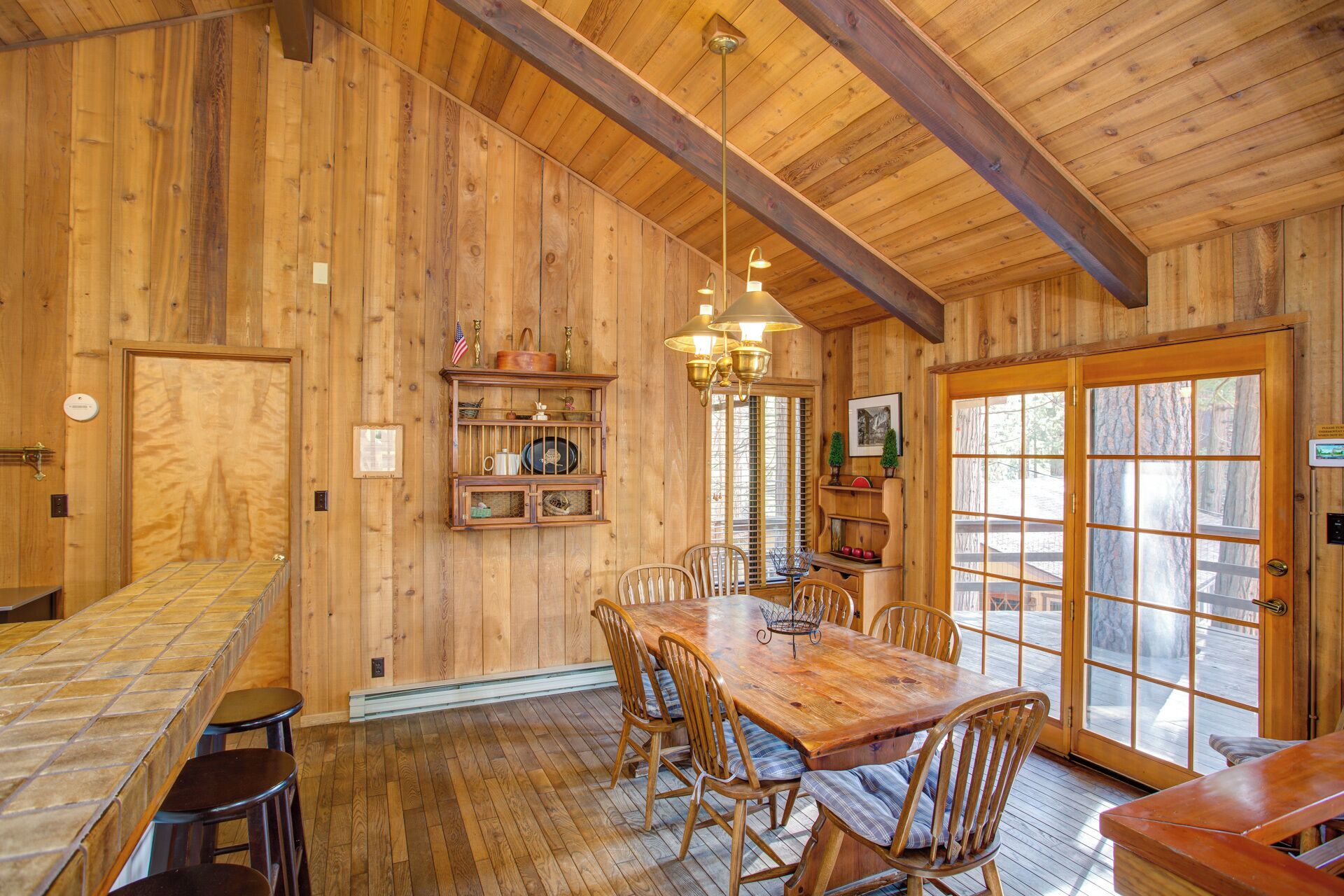 A wooden interior with a large dining table, chairs, and a bar area.