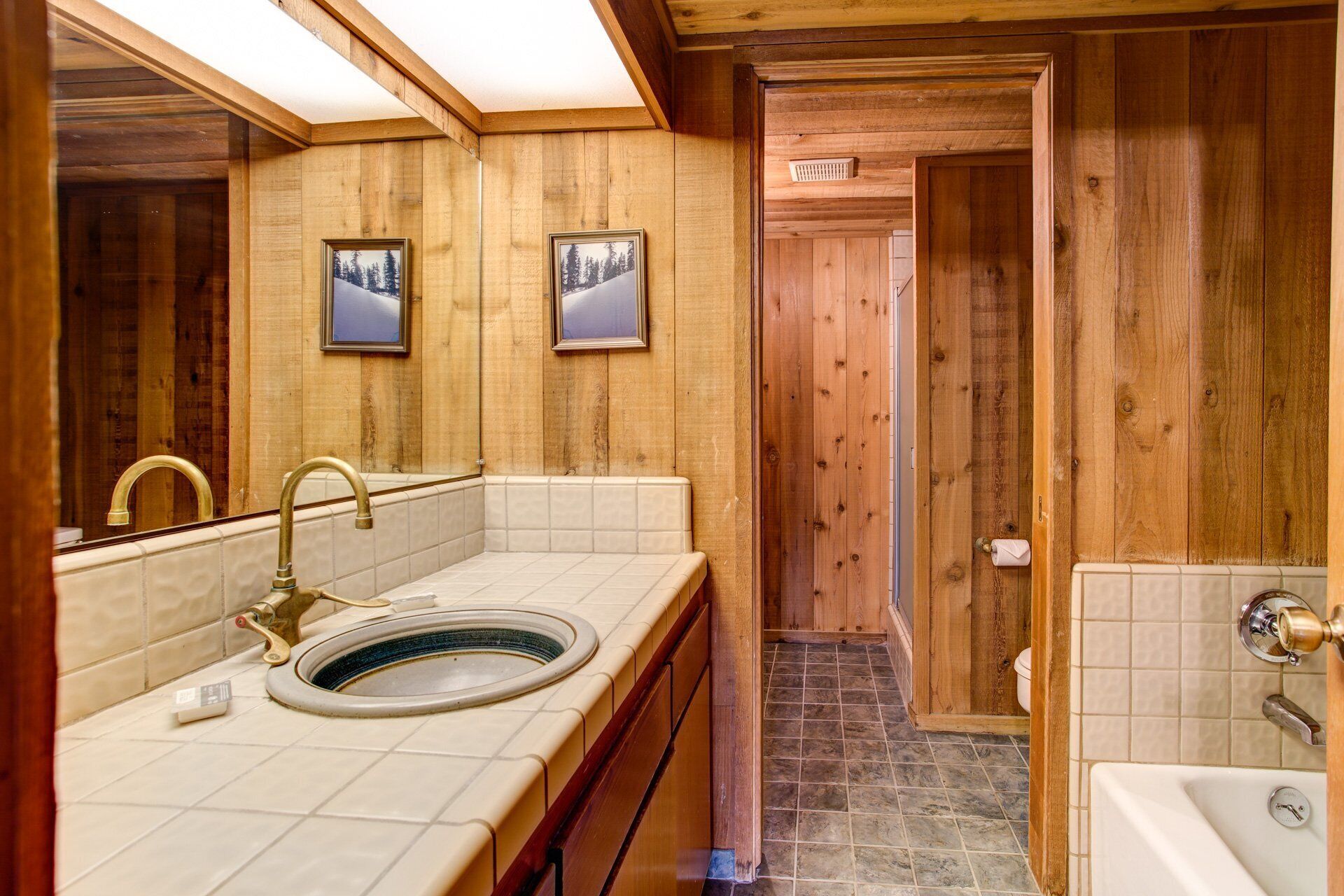 A wooden cabin bathroom with a sink, toilet, and bathtub.