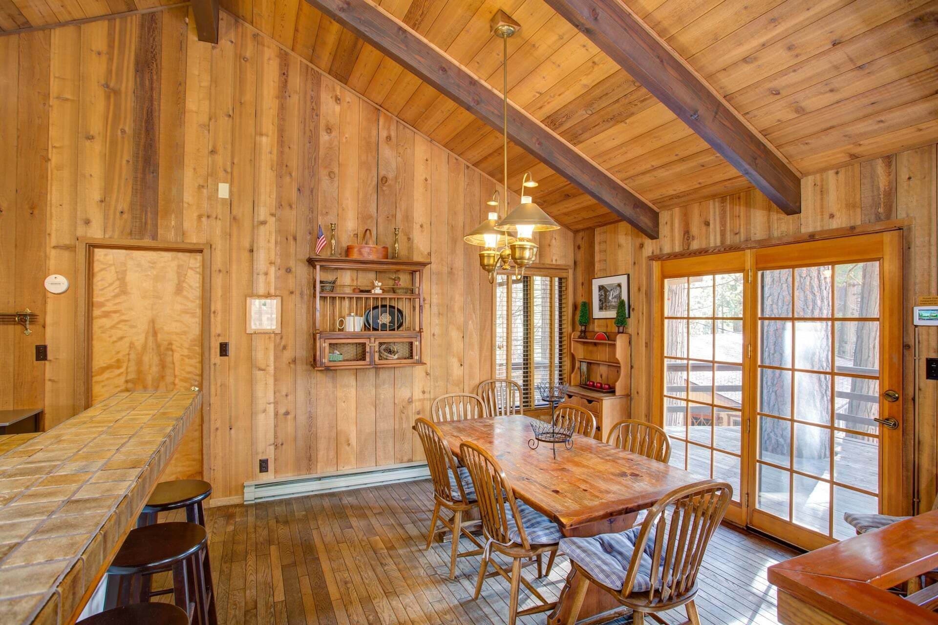 Ein Holzinterieur mit Esstisch, Stühlen, einer Bar und einem großen Fenster.
