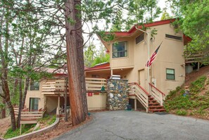 Un chalet à deux étages doté d’une façade en pierre, de balcons en bois et d’un mât pour drapeau.