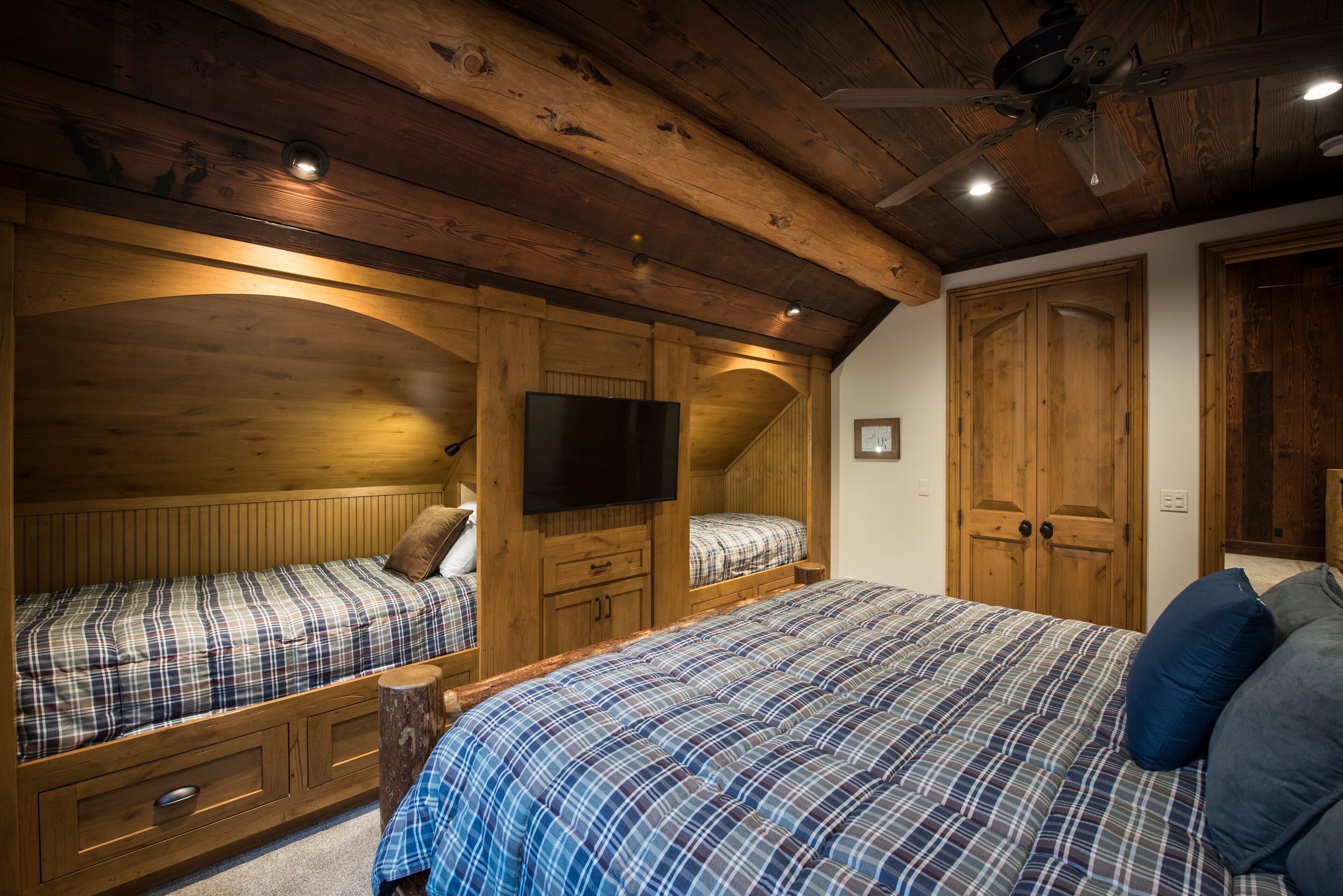 A bedroom with two beds, wooden ceiling beams, a TV, and a wooden wardrobe.